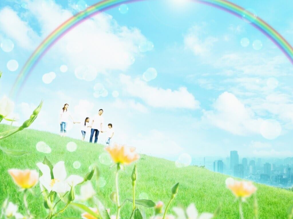 Family walking on a green hill with a rainbow and bubbles flying